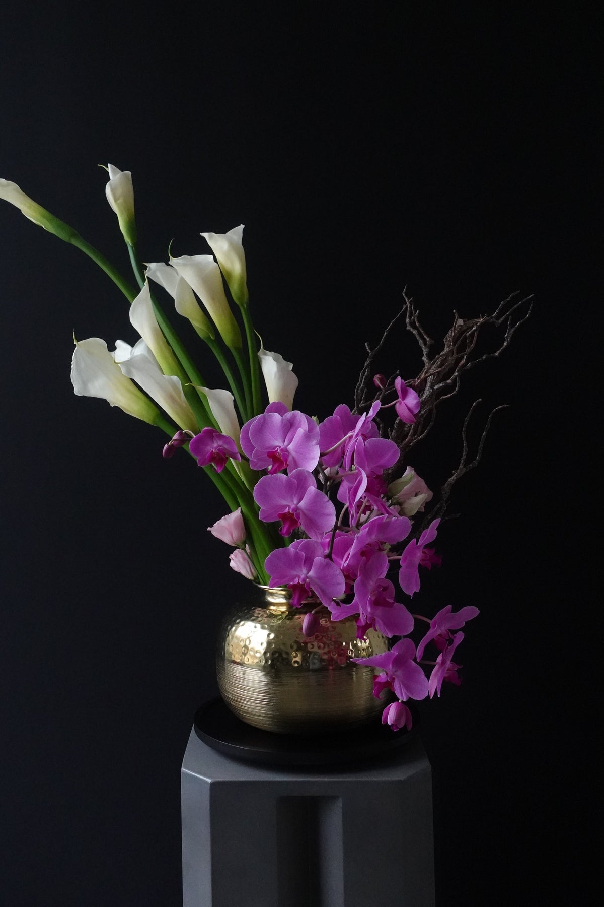 Floral arrangement with pink and white orchids emerging from a metallic vase