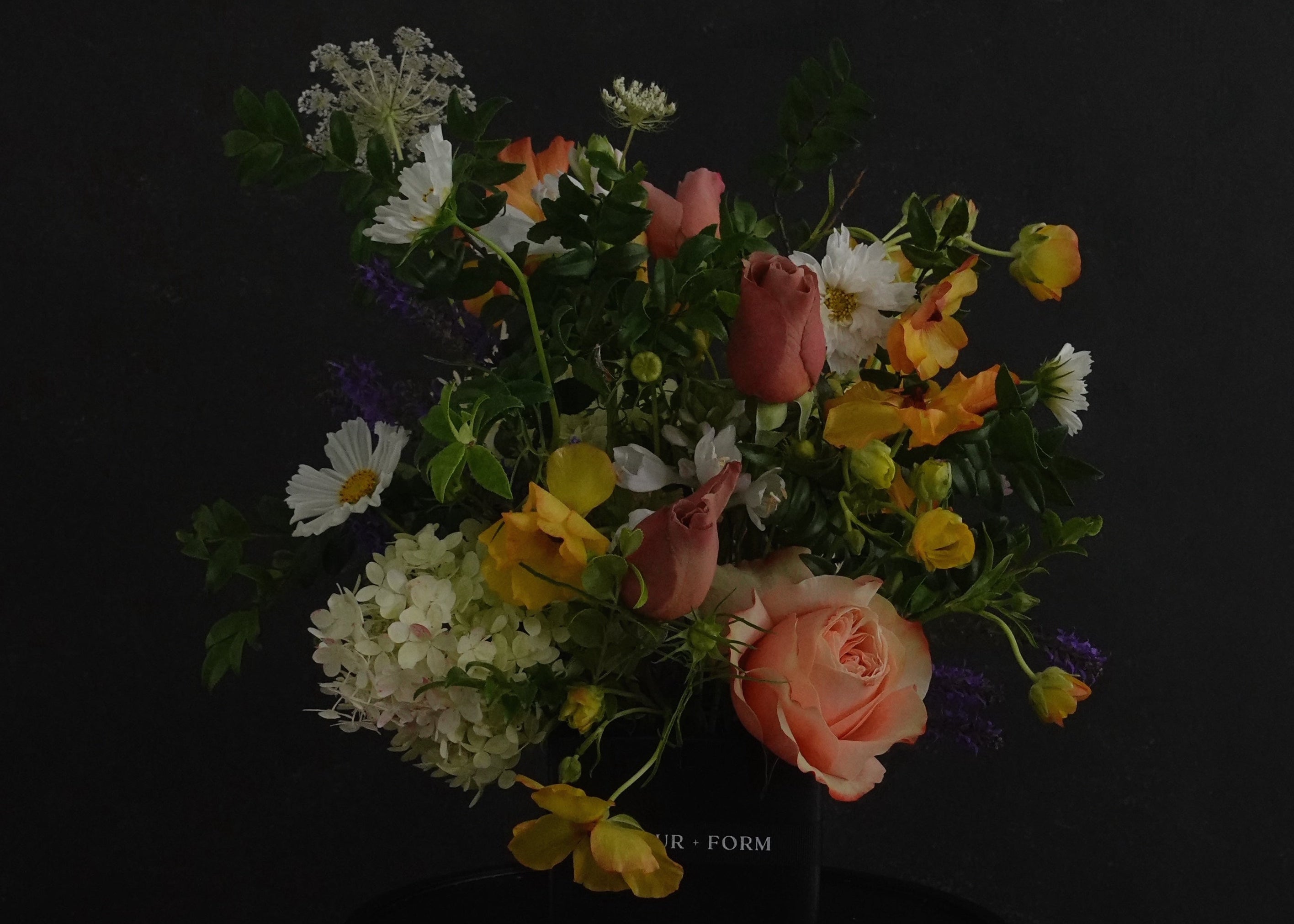 Bouquet of flowers in a dark container against a black background