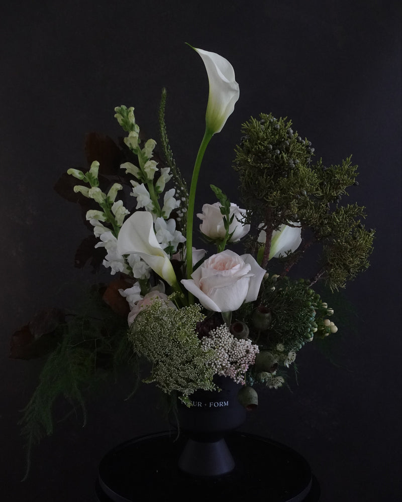 Bouquet of flowers with white calla lilies and greenery on a dark background